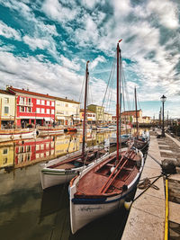 Boats moored at harbor against sky in city