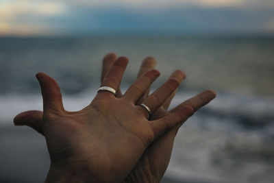 Close-up of human hands against sky
