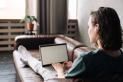 Side view of woman using digital tablet at home