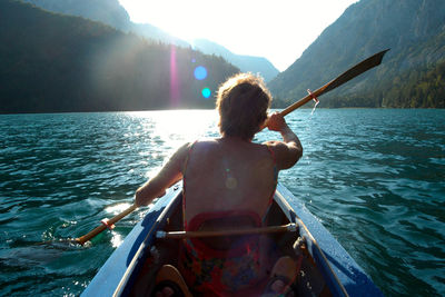 Rear view of man on boat in sea against sky