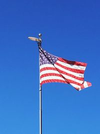 Low angle view of american flag against clear blue sky