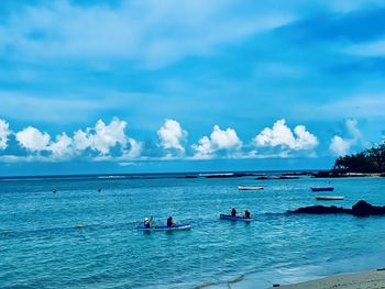 People sailing on boat at sea against sky