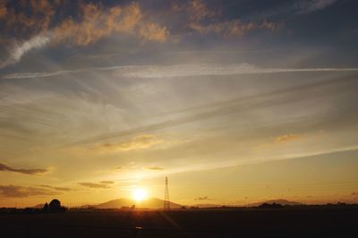 Scenic view of silhouette field against orange sky