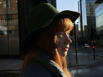 Side view of young woman wearing hat looking away in city