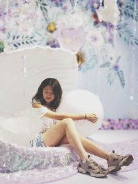 Young woman sitting on bed