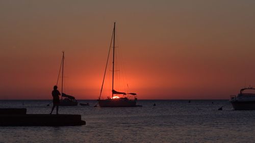 Boats in sea at sunset
