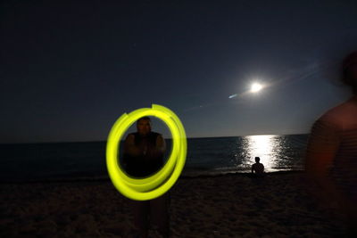 People standing at beach against sky at night