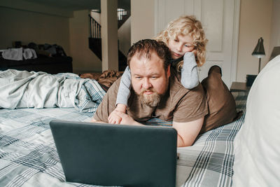 Work from home with kids children. father working on laptop in bedroom with child daughter 