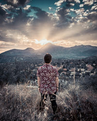 Rear view of man looking at mountains against sky