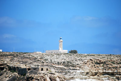 Lighthouse amidst buildings against sky