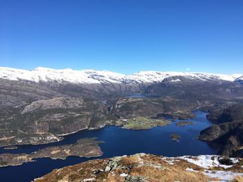 Scenic view of lake and mountains against clear blue sky