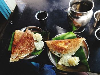 Directly above shot of dosa with coconut sauce and mashed potato on banana leaves