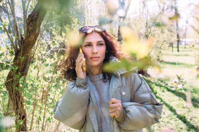 Young brunette woman talking on the phone in spring in the park