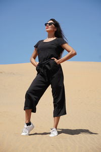 Low angle view of woman standing at beach against clear sky