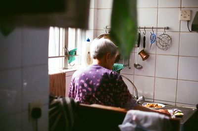 Rear view of woman preparing food in kitchen at home