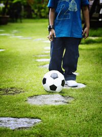 Low section of boy with soccer ball standing on field