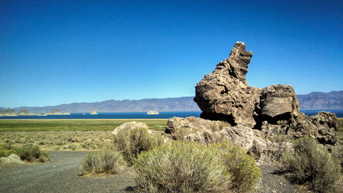 Rock formations on landscape against clear blue sky