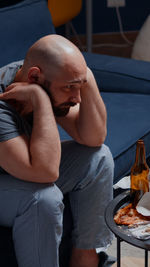 Depressed man sitting on sofa at home