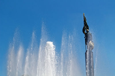 Water splashing in sea against clear blue sky