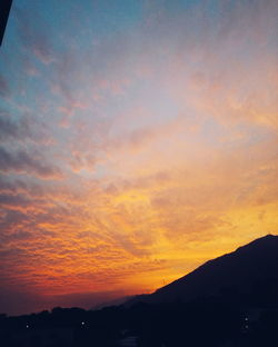 Scenic view of silhouette mountains against orange sky