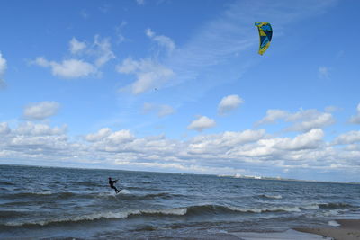 Man kiteboarding in sea against blue sky