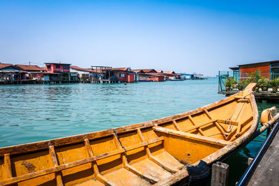 Buildings by sea against clear blue sky