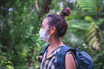 Side view point of young women backpacker wearing surgical mask in rainforest area
