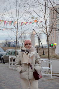 Portrait of young woman standing in city