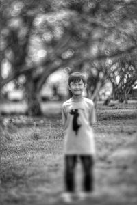 Portrait of boy standing on field in park