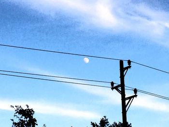 Low angle view of electricity pylon against blue sky