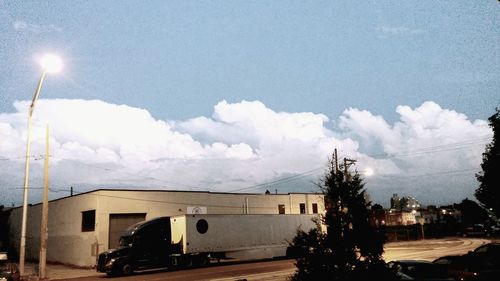 Cars on road against cloudy sky