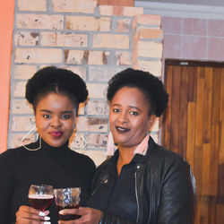 Portrait of mother and daughter toasting wines at home