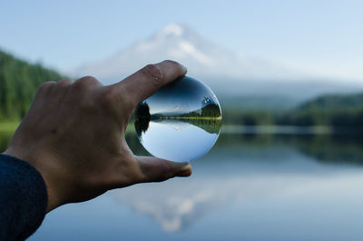 Close-up of human hand with reflection against sky