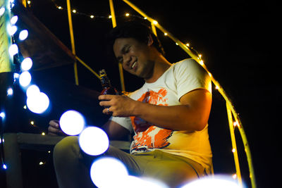 Low angle view of young woman using mobile phone at night