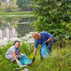 Couple collecting garbage by lake