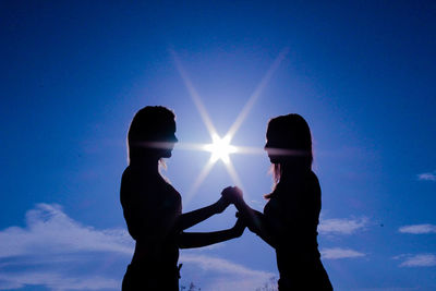 Silhouette lesbian standing against bright sun