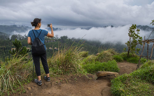 Woman taking a picture at the top of adam's peak close to ella