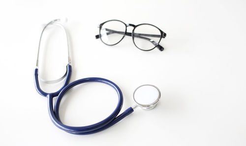High angle view of eyeglasses and stethoscope on white background