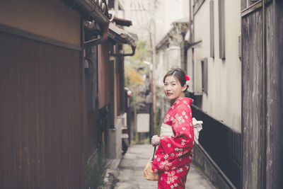 Happy woman standing against wall