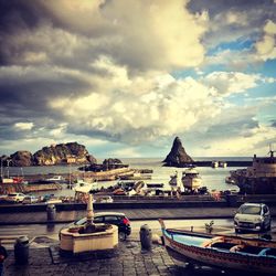 Boats in river against cloudy sky