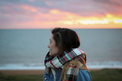 Close-up of young woman standing at beach during sunset