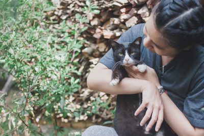 Smiling woman with cat sitting by plant