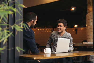 Friends talking while sitting at table in restaurant