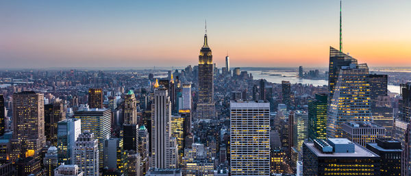 Aerial view of buildings in city against sky during sunset