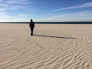 Rear view of woman on beach against sky