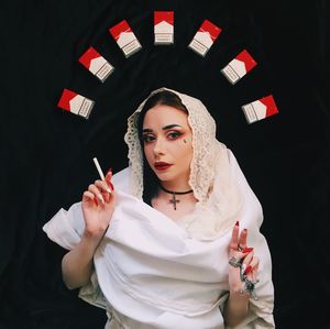 Portrait of beautiful young woman with cigarette over black background