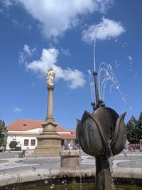 Low angle view of statue by fountain against building