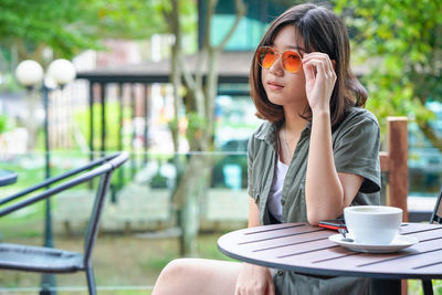 Woman wearing sunglasses sitting on table at cafe