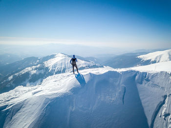 Rear view of man standing on snowcapped mountain