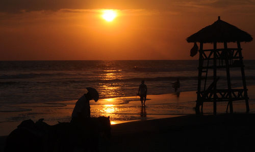 Silhouette people at beach during sunset